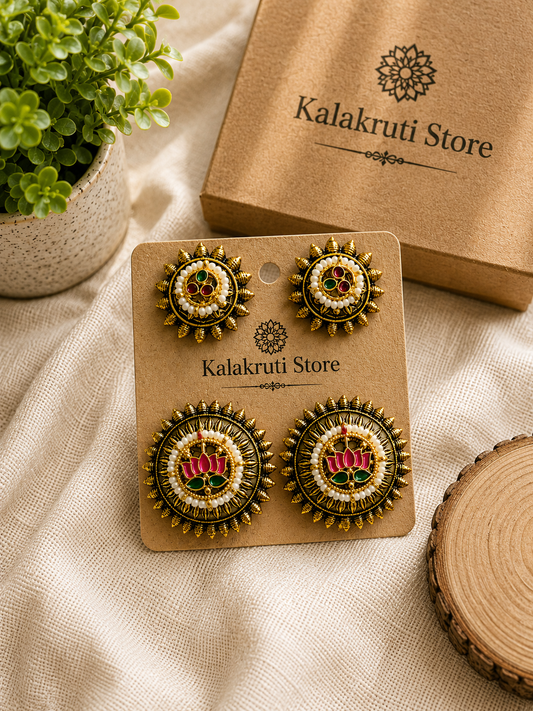 A pair of ornate gold-toned statement earrings displayed on a brown kraft card labeled Kalakruti Store, with the matching box and a small potted plant in the background on a beige fabric surface.